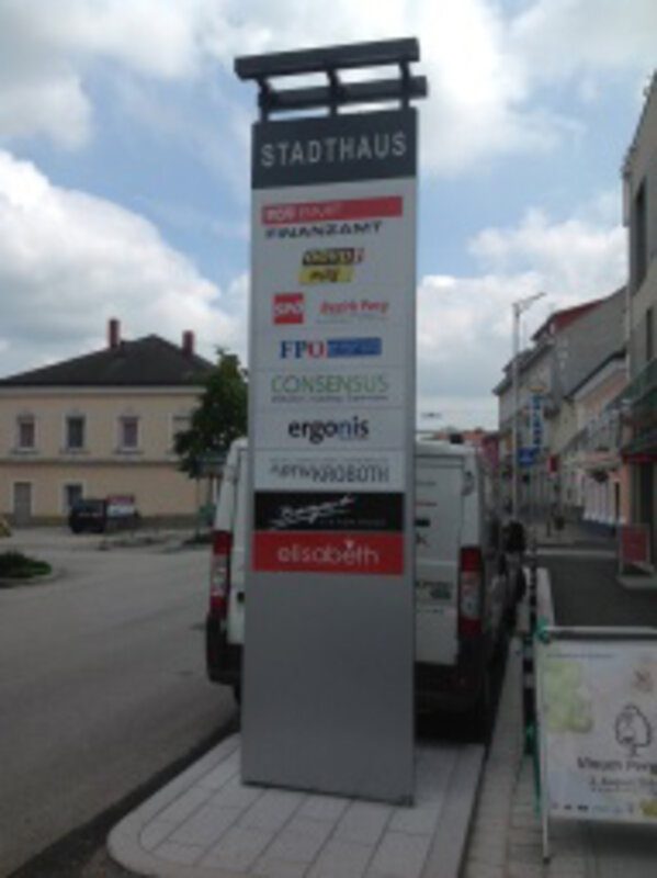 Pylon mit Firmenlogos an einer Straße